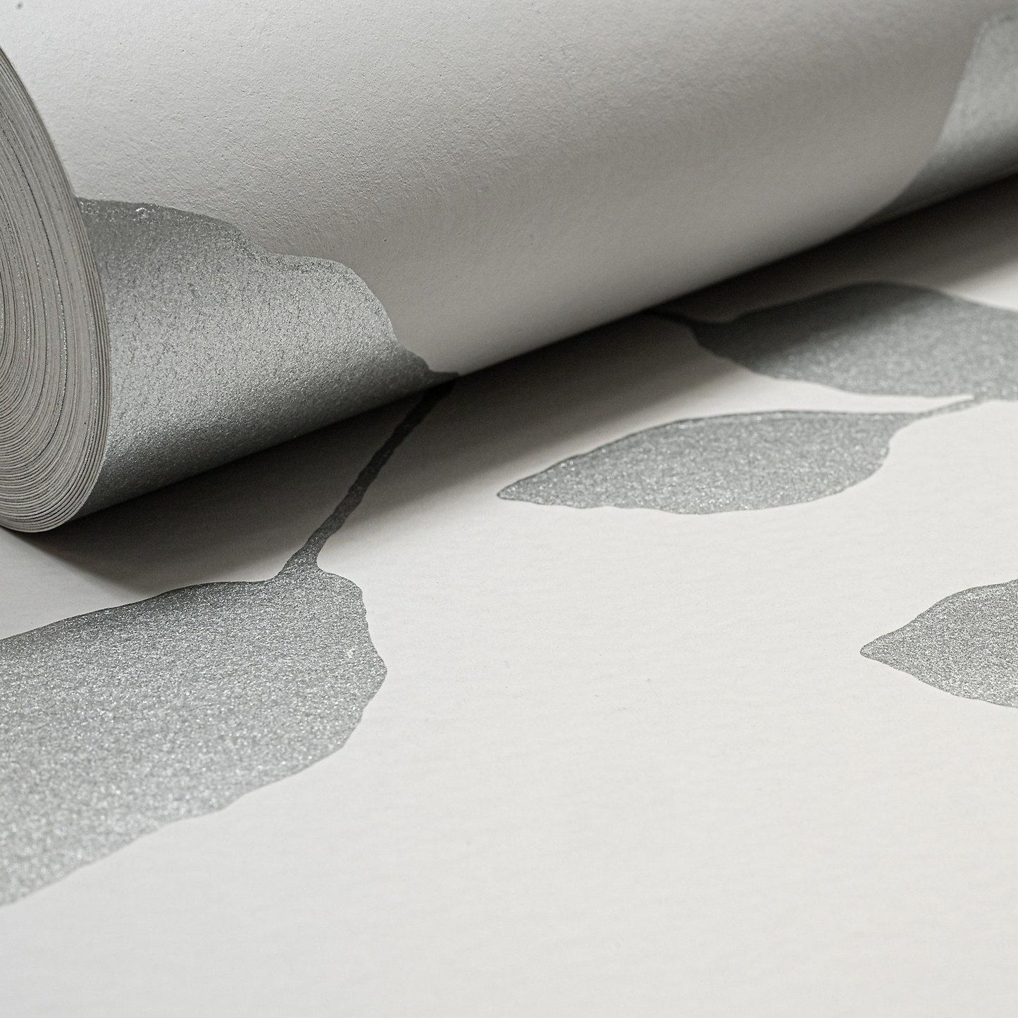 Silver Shadow Floral Wallpaper roll close up showing leaf pattern and silver finish