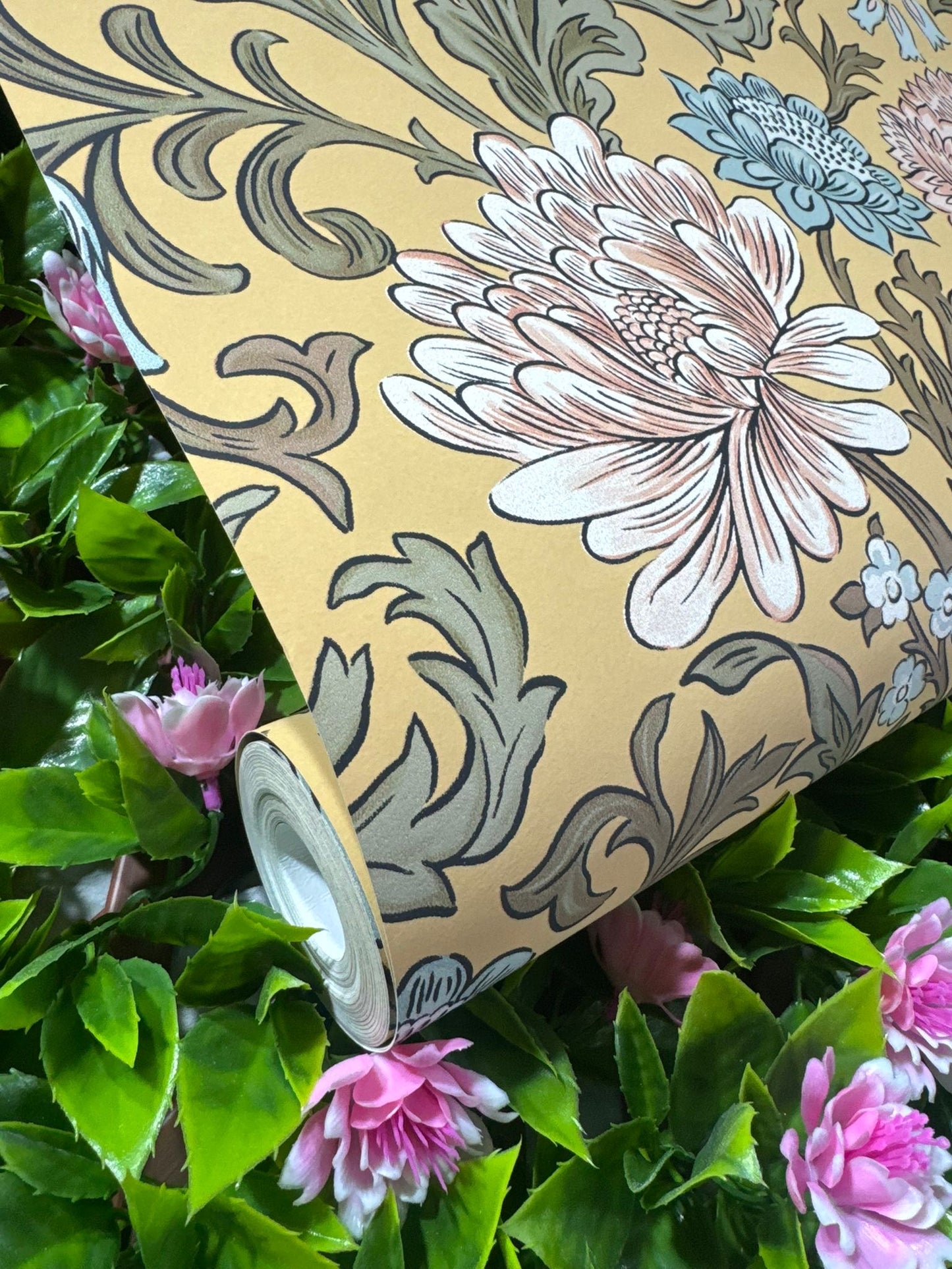 Mustard Floral Wallpaper roll amongst pink flowers and green foliage